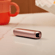 The Ploom AURA Rose Gold device placed on a table.